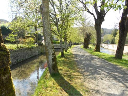 a tree lined path next to a river at Auberge de l'Abbatiale in Auberive