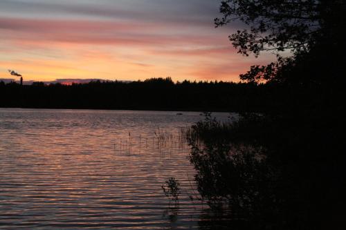 a sunset over a body of water with trees at Forsbacka Wärdshus in Forsbacka
