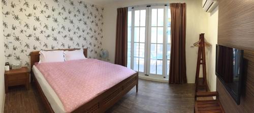 a bedroom with a bed and a tv and a window at Kenting Lian Nan Wan in Nanwan