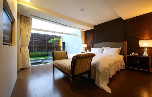 a bedroom with a bed and a chair and a window at Elan-Motel in Wujie