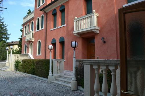 Edificio grande de color naranja con porche y balcón en B&B Villa Carli, en Caneva