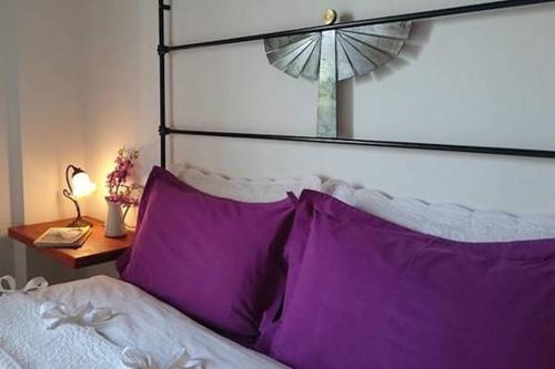 a bed with purple pillows and a lamp on a table at Helicon Muses Friendly Mountain B&B Guesthouse in Evangelístria