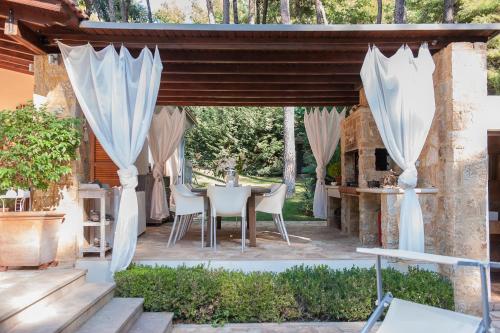 a patio with white curtains and a table and chairs at Naftilos Villa Sani in Sani Beach