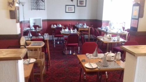 a restaurant with wooden tables and red chairs at Elmfield in Blackpool