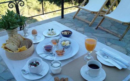 a table with plates of food and drinks on it at Helicon Muses Friendly Mountain B&B Guesthouse in Evangelístria