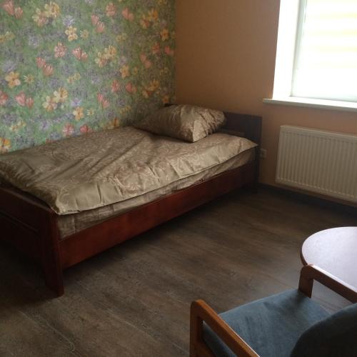 ein kleines Schlafzimmer mit einem Bett mit Blumentapete in der Unterkunft Svečių namai in Ryškėnai