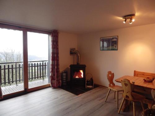 - un salon avec une cheminée, une table à manger et un poêle à bois dans l'établissement gites Les Bleuets, à Vagney