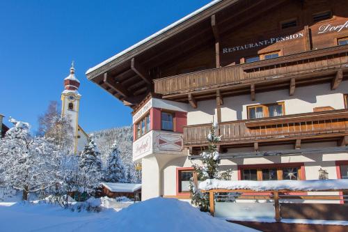 a building in the snow with a clock tower at Dorfcafe Unken Hotelpension sWirtshaus im Dorf in Unken