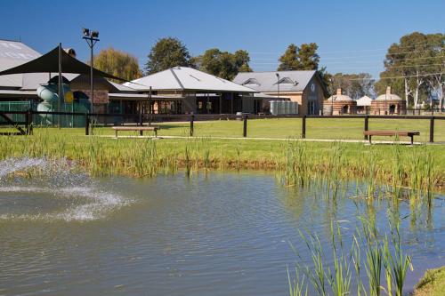 a pond in a park with benches and a building at Potters Apartments in Cessnock