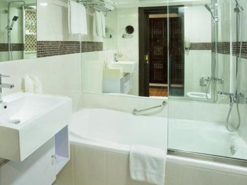 a white bathroom with a shower and a sink at Arabian Courtyard Hotel & Spa in Dubai