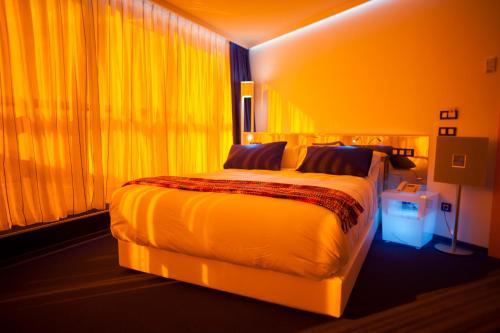 a bedroom with a large bed with yellow curtains at Resotel in Villares de la Reina