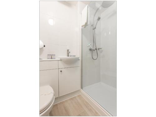 uma casa de banho branca com um chuveiro e um WC. em Sandpiper em Poole