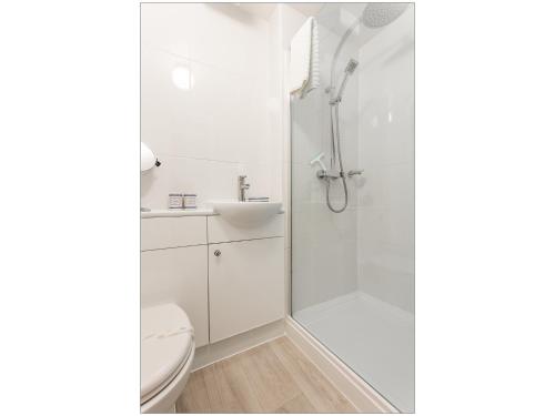 a white bathroom with a shower and a toilet at Sandpiper in Poole