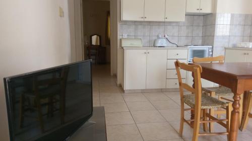 a kitchen with a television and a table with chairs at New York Plaza Hotel Apartments in Paphos City