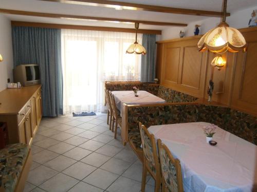 a dining room with two tables and a kitchen at Gästehaus Alpenruh in Holzgau