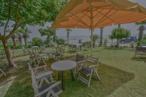 a group of tables and chairs under an umbrella at Hotel Achillion in Makrýgialos
