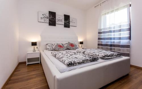 a large white bed in a bedroom with a window at Apartments Zeljko B in Šilo