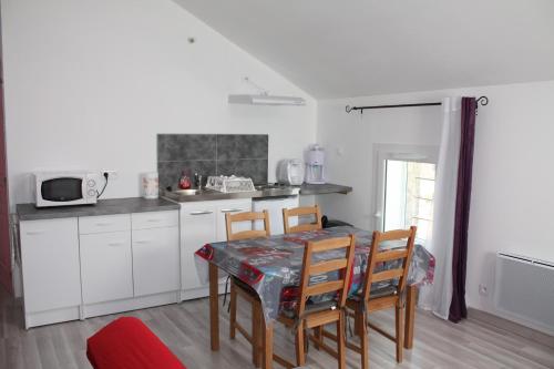 une cuisine avec une table et des chaises et une cuisine avec des armoires blanches dans l'établissement L'oiseau bleu, à Salin-de-Giraud