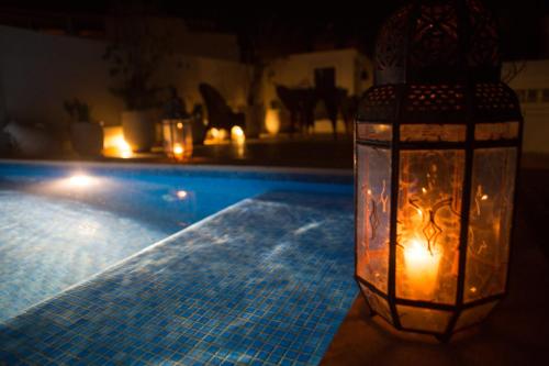 a candle in a lantern next to a swimming pool at Dar Kika Salam By DKS in Rabat