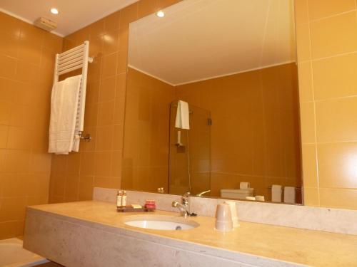 a bathroom with a sink and a large mirror at Douro Hotel Porto Antigo in Cinfães