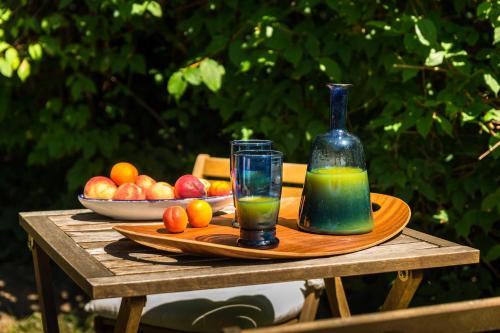 a table with a bottle of juice and a plate of fruit at Maison des Bois in Bièvres