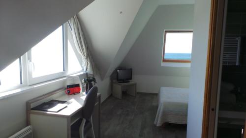 a room with a desk and a bed and windows at Le Relais de la Pointe du Van in Cléden-Cap-Sizun