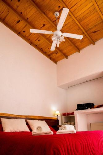 a bedroom with a red bed with a ceiling fan at Posada La Rosita in Santa Rosa de Calamuchita