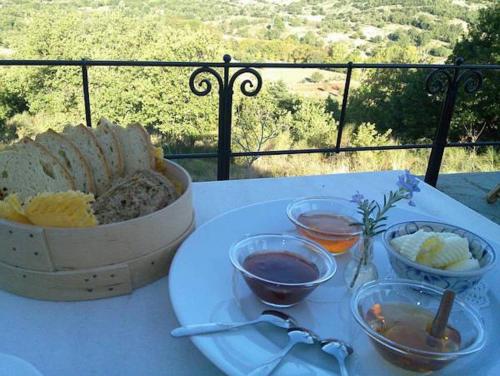 a table with a plate of food and a basket of bread at Helicon Muses Friendly Mountain B&B Guesthouse in Evangelístria