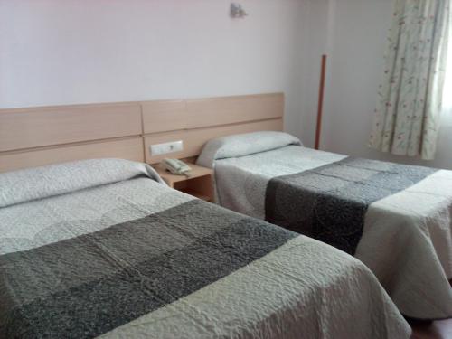 a hotel room with two beds and a telephone between them at Nap Carta Puebla in Oviedo