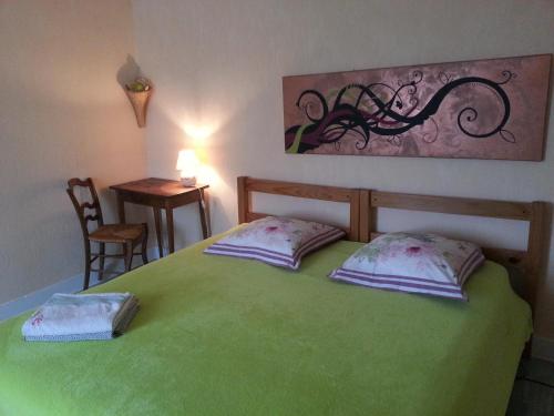um quarto com uma cama verde e 2 almofadas em L'Orme-Vial em Saint-Galmier