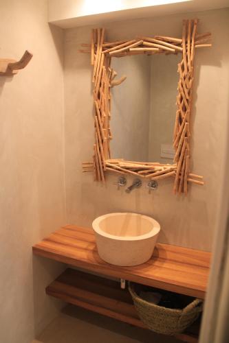 a bathroom with a bowl on a wooden counter with a mirror at S'Esparteria Hotel in Ciutadella