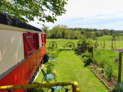 a red train parked in a garden with chairs at La Roulotte De Lola - Chambre d'hôtes in La Celle