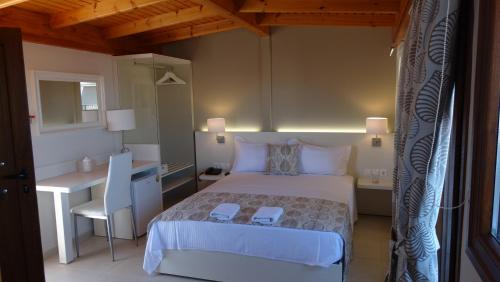 - une chambre avec un lit blanc, un bureau et une table dans l'établissement Athos Guest House Pansion, à Ouranoupoli