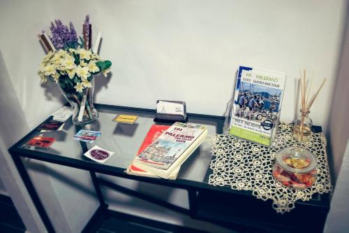 a glass table with a vase of flowers and magazines at La Terrazza sul Centro in Palermo