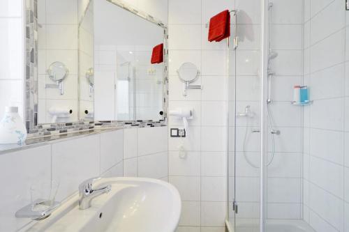 a white bathroom with a sink and a shower at Hotel Engelhorn in Leimen