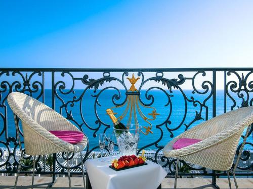a white table topped with flowers next to a balcony at Hôtel Le Royal Promenade des Anglais in Nice
