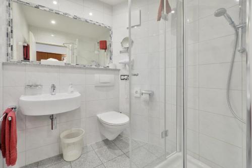 a bathroom with a toilet and a sink and a shower at Hotel Engelhorn in Leimen
