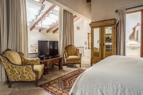 a bedroom with a bed and a tv and chairs at Hacienda San Gabriel de las Palmas in Amacuzac