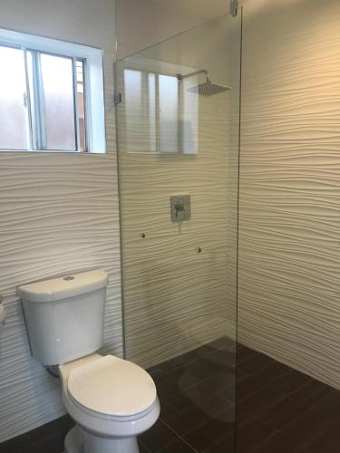 a bathroom with a toilet and a glass shower at La Bonita Inn Motel in Long Beach