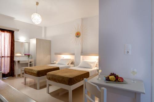 a bedroom with two beds and a table with a tableasteryasteryasteryasteryastery at Kamarela Studios in Kamari