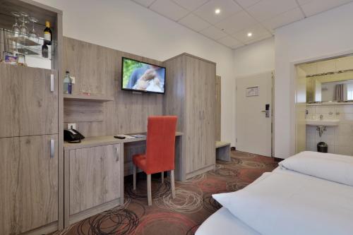 a hotel room with a desk and a tv on the wall at Hotel Engelhorn in Leimen