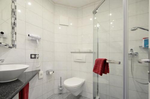 a bathroom with a toilet and a sink and a shower at Hotel Engelhorn in Leimen