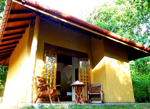 a small yellow house with chairs and a table at Bissa Villa in Habarana