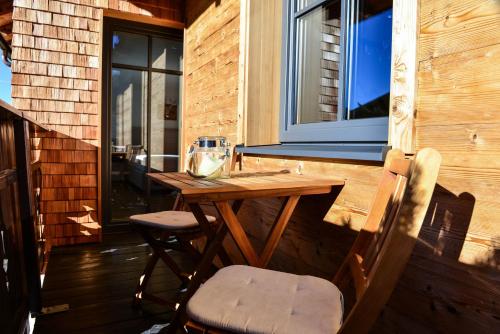 a wooden table and chairs on a porch with a window at Sonn Alpin - Ferienwohnungen in Grän