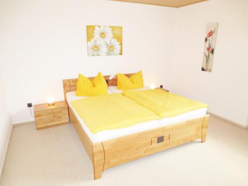 1 dormitorio con cama de madera y almohadas amarillas en Ferienunterkunft Börner en Ehlscheid