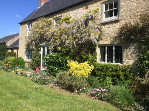 a stone house with flowers in front of it at Mill Farm in Milton Keynes