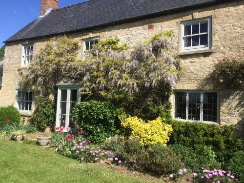 an old stone house with flowers in the front yard at Mill Farm in Milton Keynes