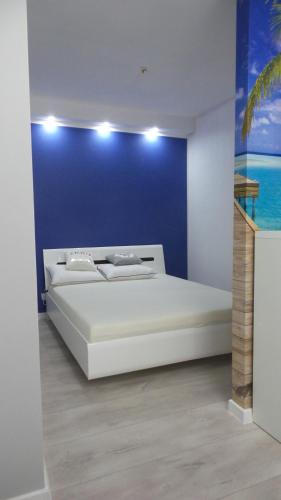 una camera con un letto bianco e una parete blu di Apartament Polna a Szczecinek