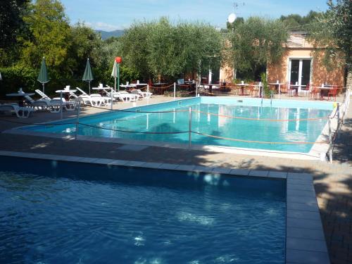 a large swimming pool with tables and chairs in front of a building at Villaggio RTA Borgoverde in Imperia