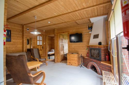 a living room with a fireplace in a log cabin at Domek Mikołajki in Mikołajki